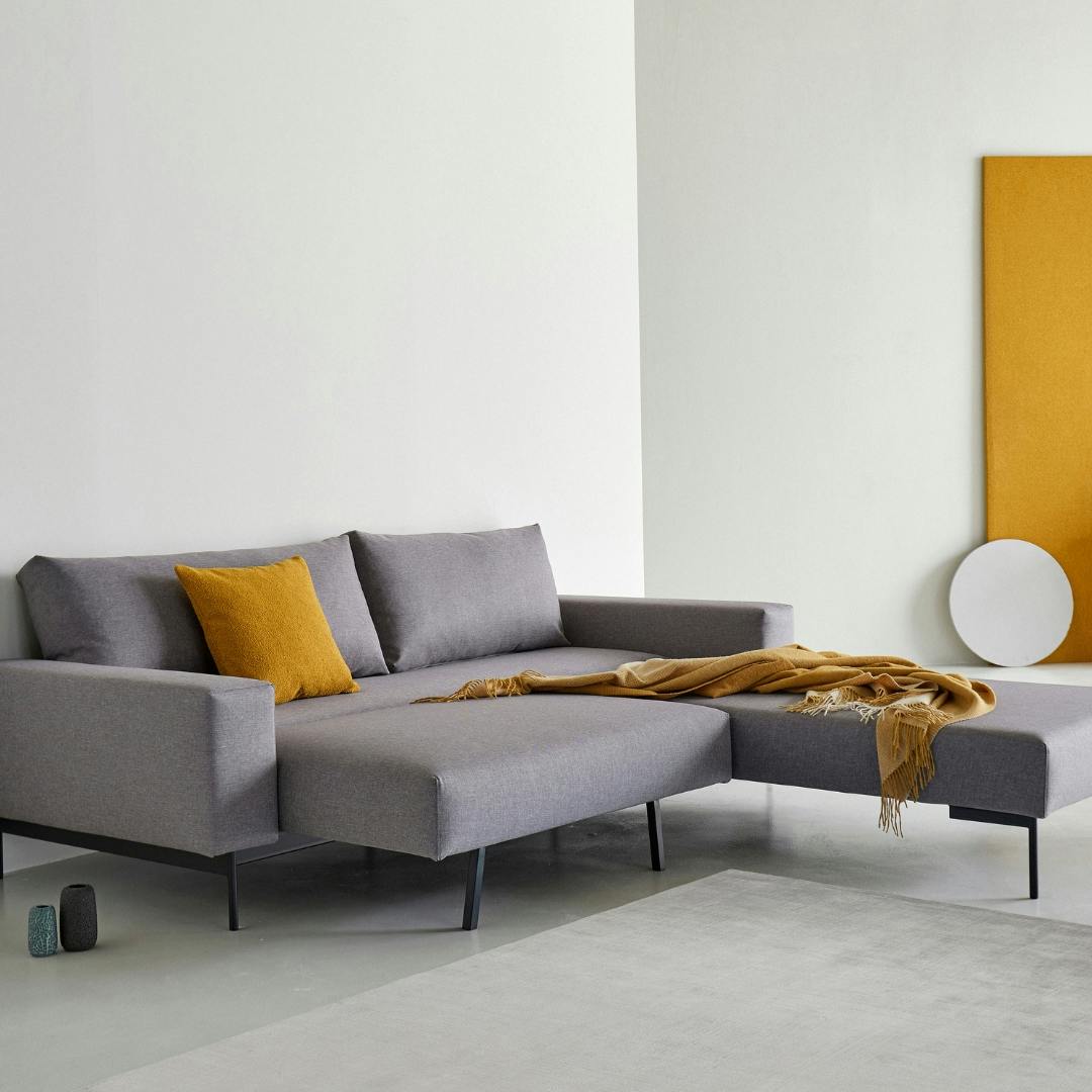 graues Klappsofa L-Form in Wohnzimmer mit Teppich